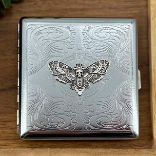 Dark academia pocket case featuring a silver skull moth on an ornate stamped metal background