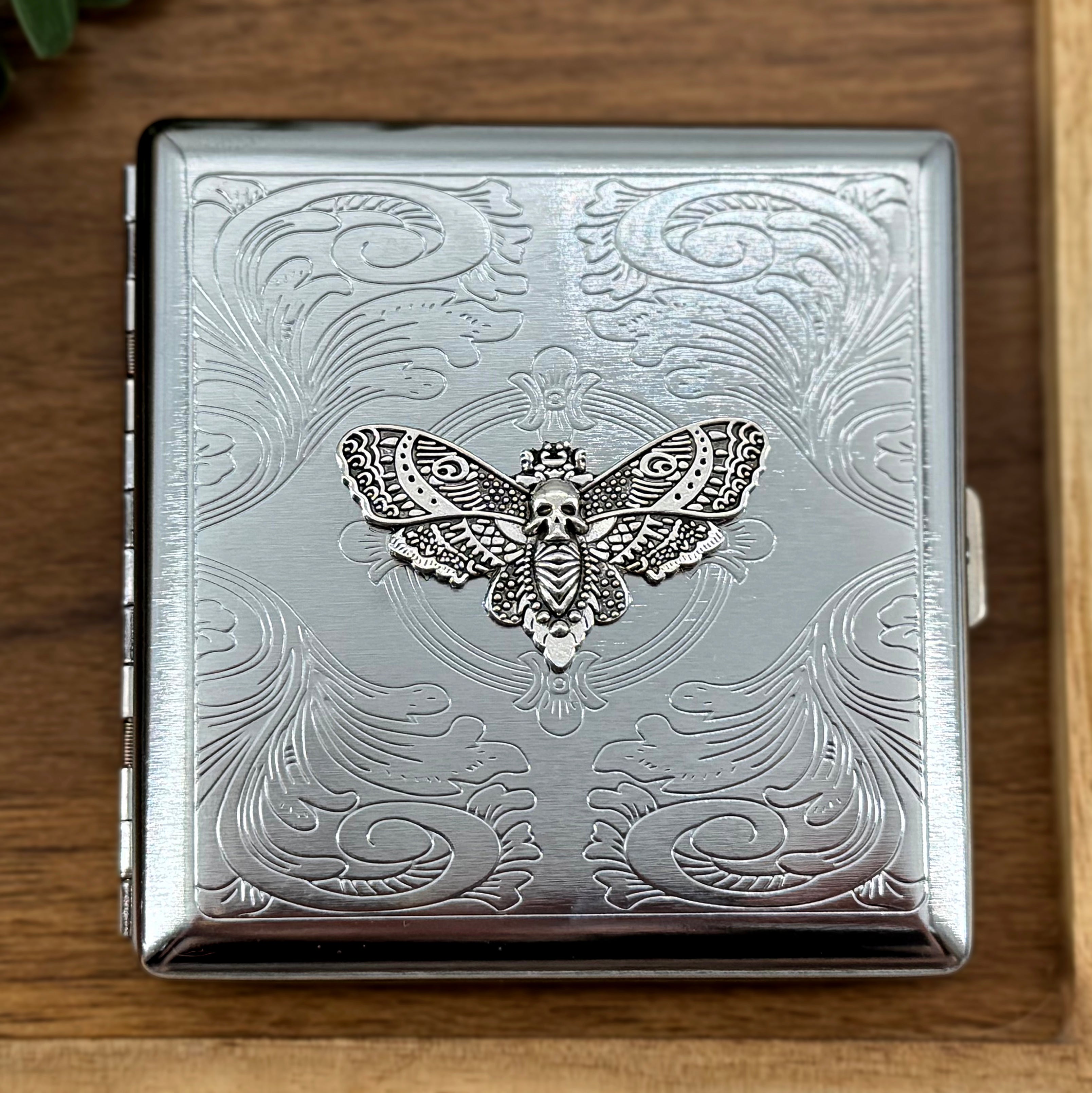 Dark academia pocket case featuring a silver skull moth on an ornate stamped metal background