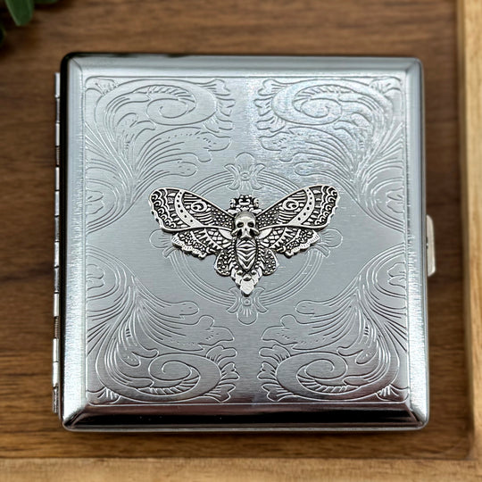 Dark academia pocket case featuring a silver skull moth on an ornate stamped metal background