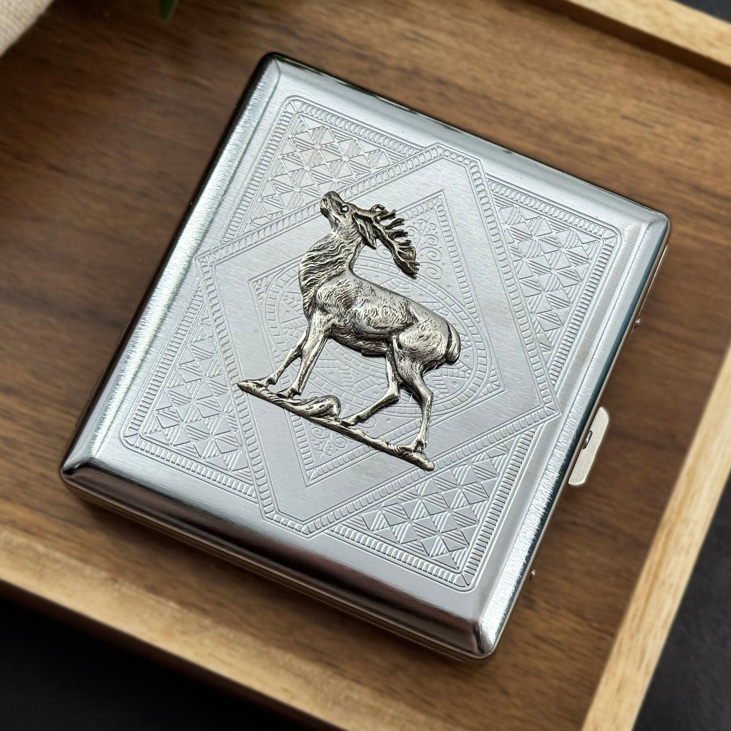 Silver-toned metal card holder featuring a detailed elk over layered geometric patterns