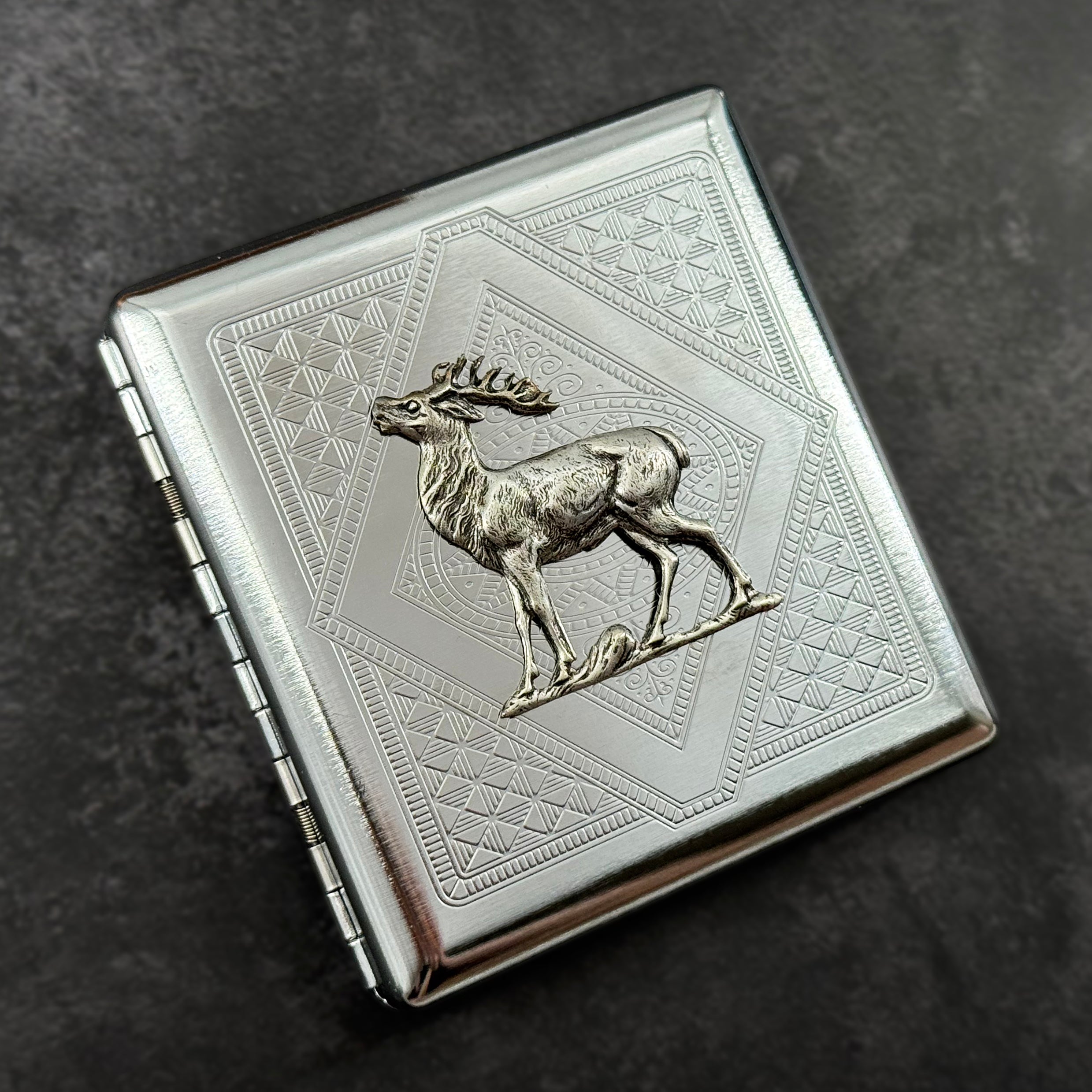 Silver metal cigarette case with woodland deer centerpiece and angular stamped design