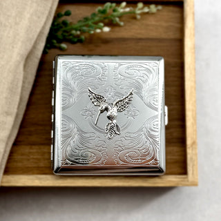 Nature-inspired cigarette case with raised hummingbird accent and decorative engraved background