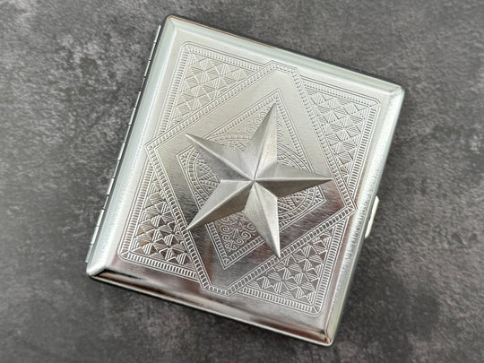 Close-up of raised silver nautical star on stamped metal cigarette case