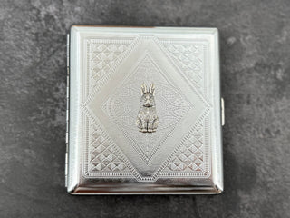 Handmade silver cigarette case featuring a small rabbit centerpiece and geometric metal pattern
