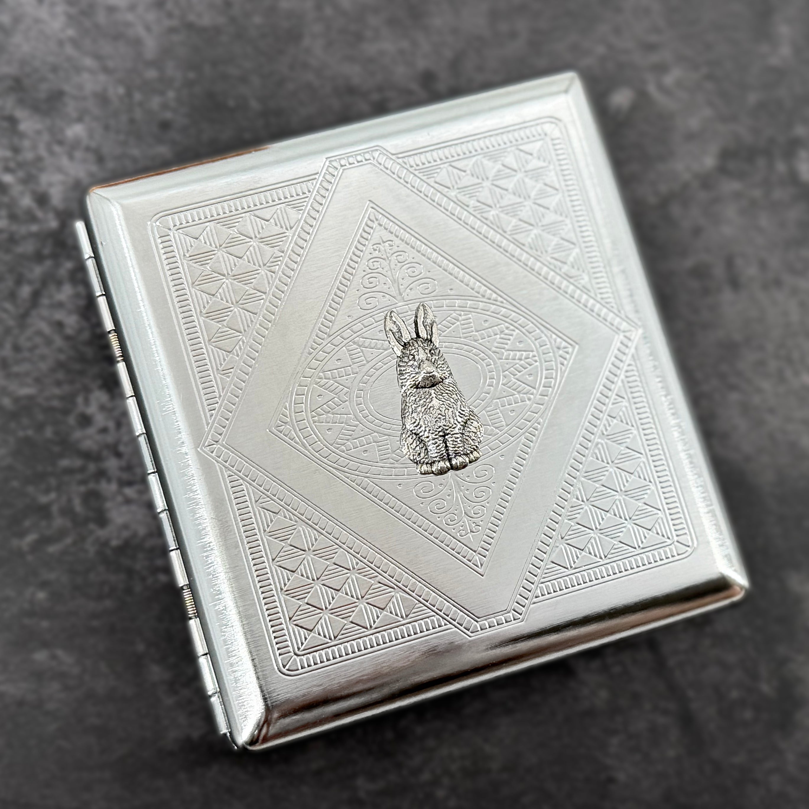 Silver rabbit card holder with textured stamped metal background and decorative geometric design