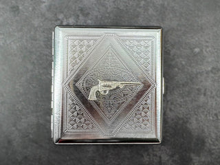 Silver revolver card holder with decorative geometric stamped metal background.