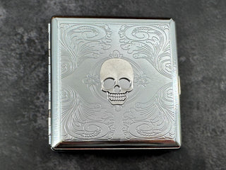 Silver skull metal cigarette case with ornate scrollwork background