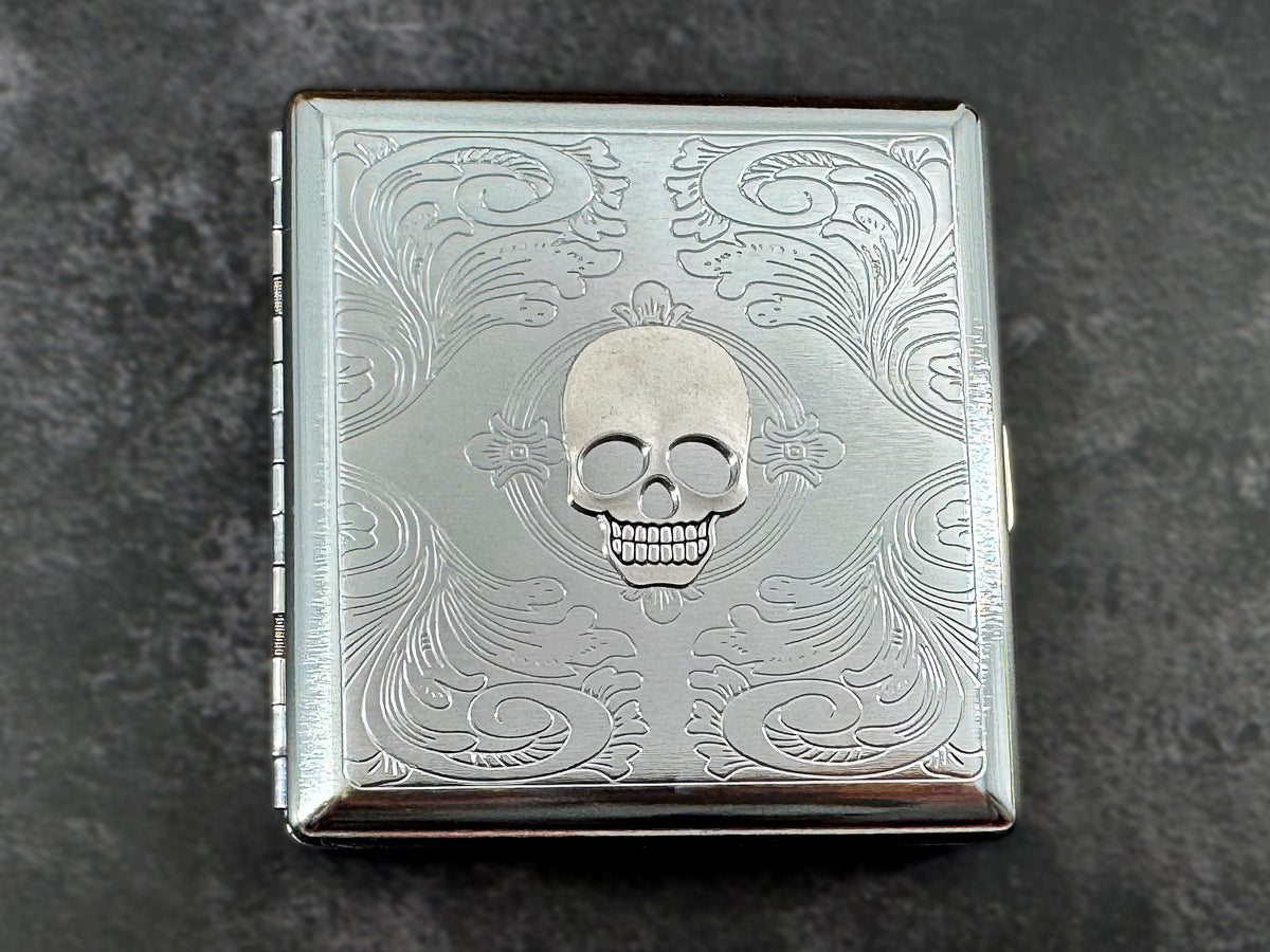 Silver skull metal cigarette case with ornate scrollwork background