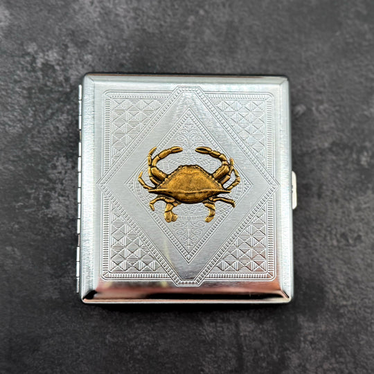Crab cigarette case with raised bronze crab on silver stamped metal background