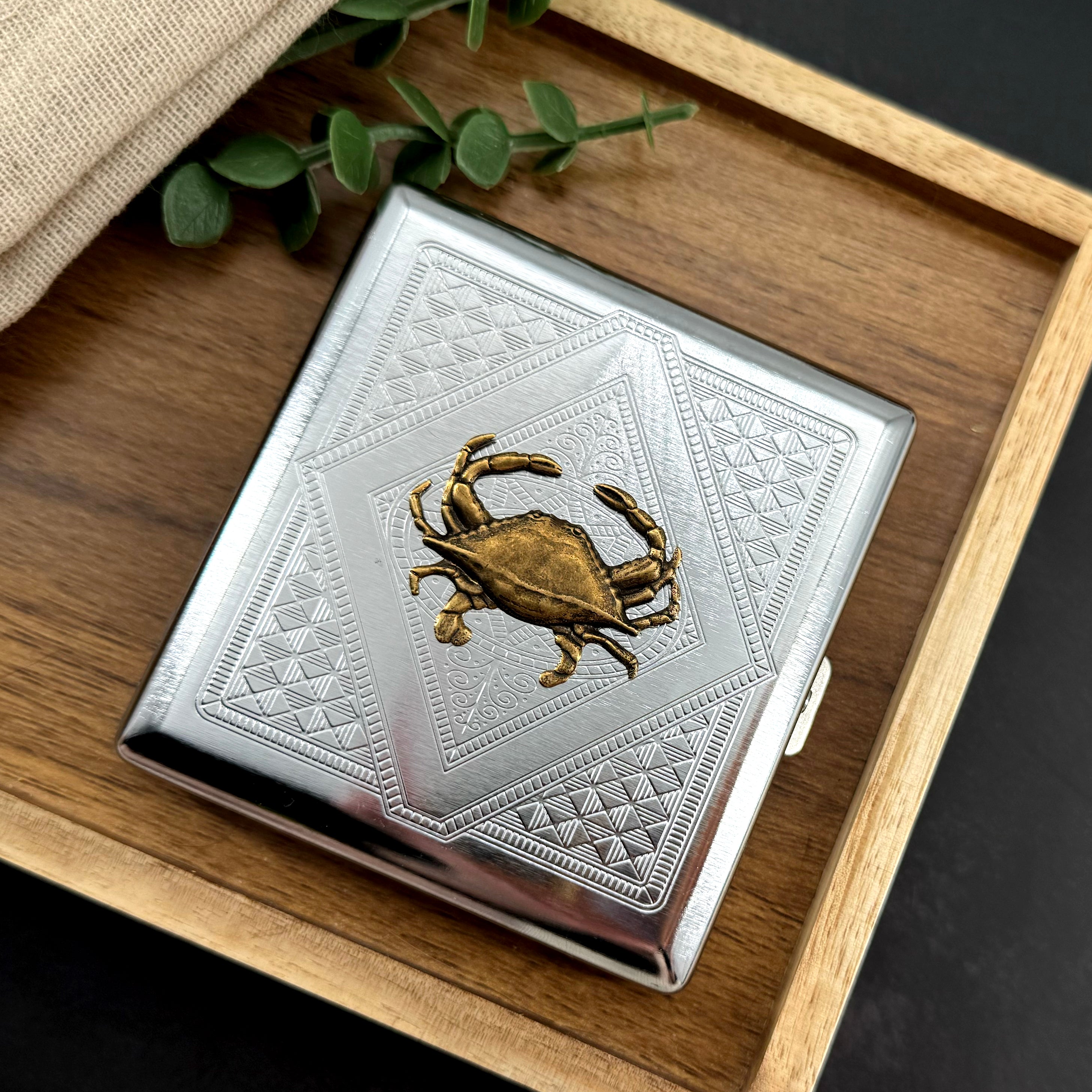 Handmade metal crab case featuring geometric engraved design and bronze crab centerpiece