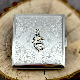 Handmade unicorn cigarette case displayed on natural wood slice