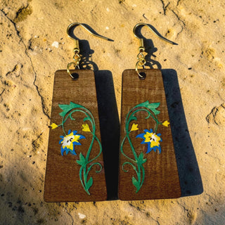Wooden earrings with floral designs on a textured surface