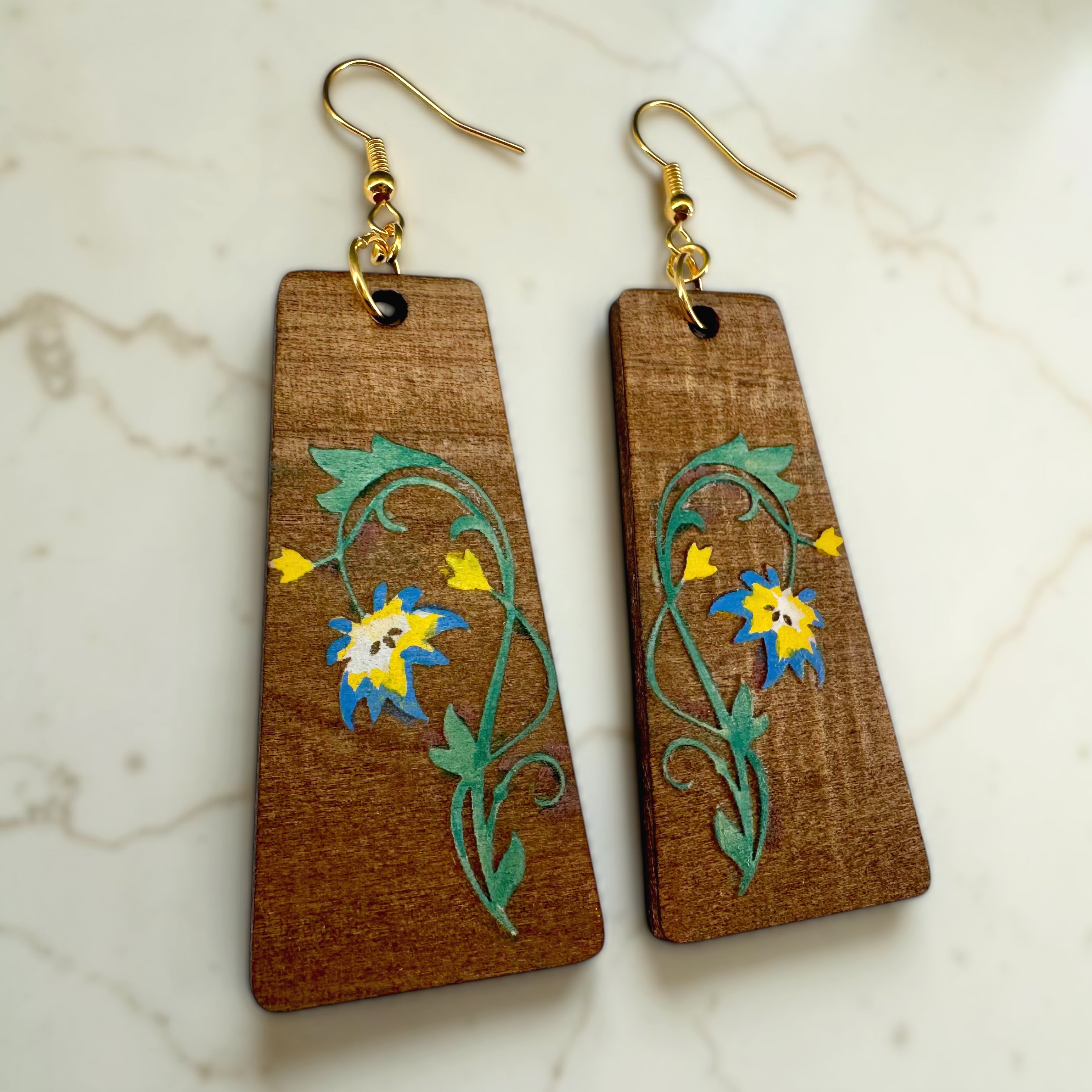 Wooden earrings with floral designs on a marble surface