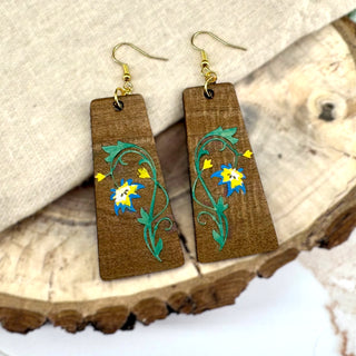 Wooden earrings with floral designs on a wooden surface