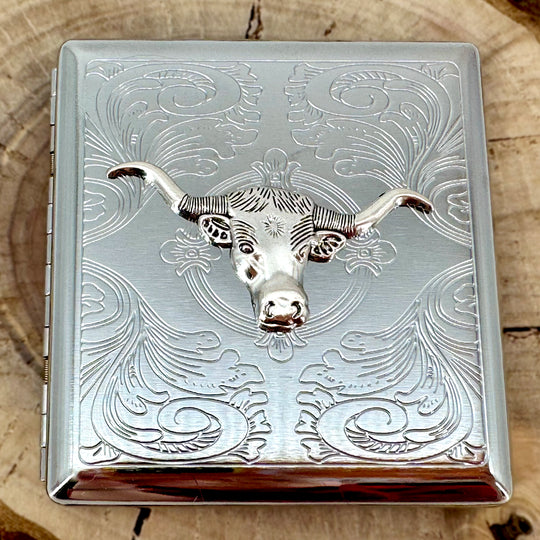 Western longhorn pocket case displayed on a natural wood slice with engraved silver finish