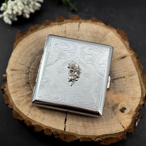 Classic metal card case with intricate stamped border, secure snap closure, and polished silver finish