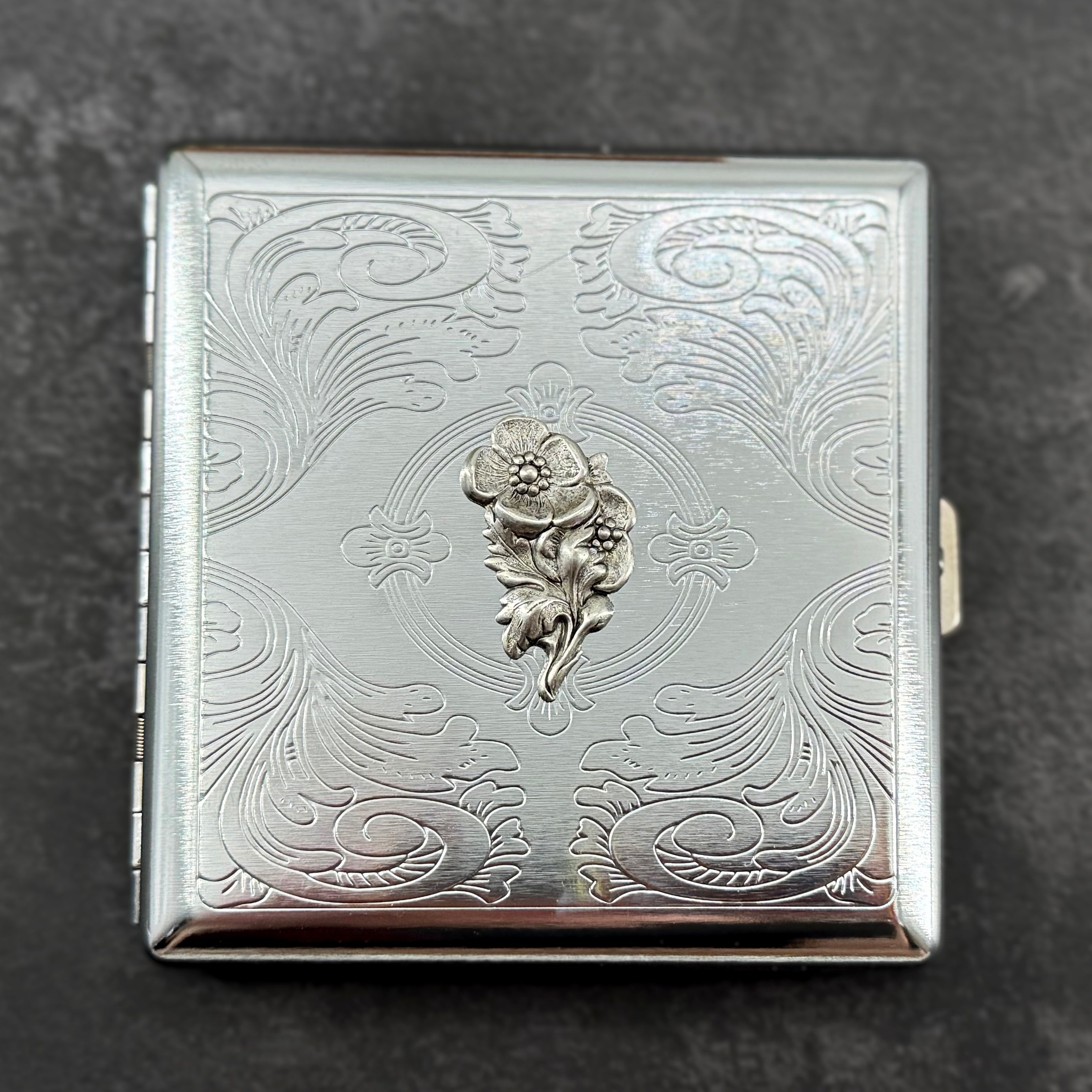 Compact silver cigarette case showcasing an elegant textured stamping with vintage-inspired detailing