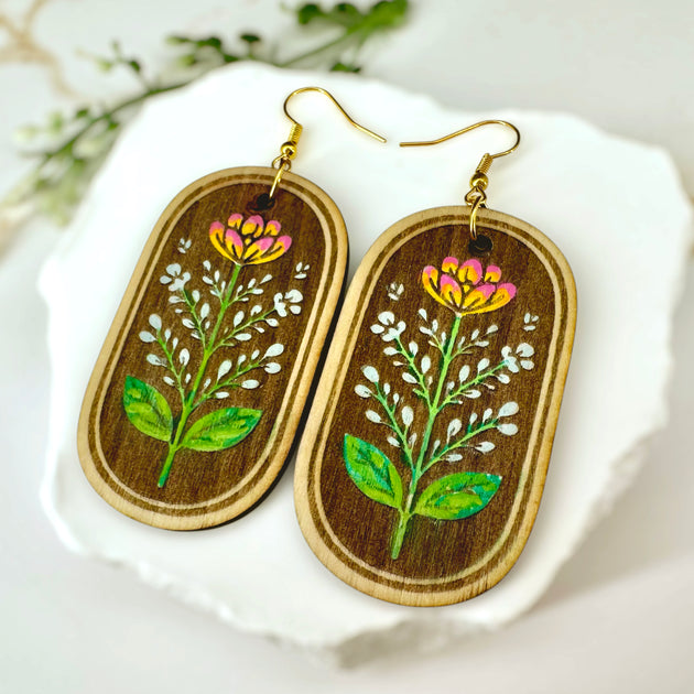 Close-up of hand-painted wildflower detail on wooden earrings by Harmless Habit Studio