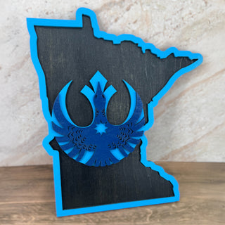 Blue cutout of a symbol inside a black outline of a state on a wooden surface with a marble background